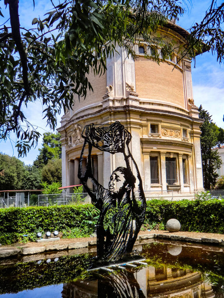 Итальянский художник Пьетро Руффо со своей работой "Il Migrante" (иммигрант) на выставке "Возвращение к природе 2021" у исторической водяной цистерны "Serbatoio dell Aqua Marcia" на площади Piazzale dei Daini в парке Вилла Боргезе - Фото, изображение