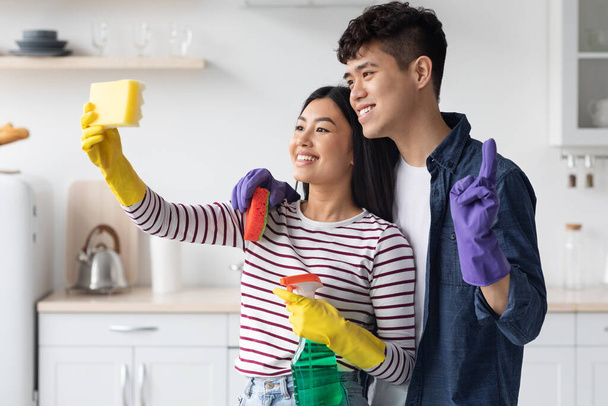 Amoroso asiático pareja tomando selfie mientras limpieza cocina - Foto, Imagen