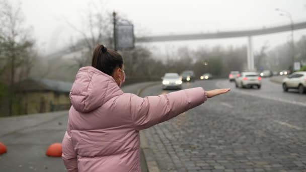 Jeune femme debout sur la route à l'extérieur levant la main de côté attraper un taxi - Séquence, vidéo