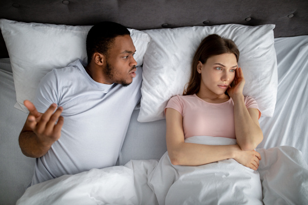 Millennial gemischtrassiges Paar streitet im Bett, ist wütend, steht vor Familienproblemen, Draufsicht - Foto, Bild