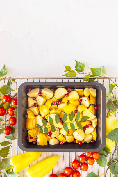 The concept of a vegetarian picnic and healthy food. Vertical, healthy, food composition with a baking tray with farm, young potatoes, berries and seasonal vegetables on a grill with copy space - Photo, Image