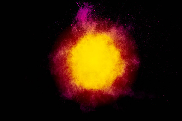 Rotgelbes Pulver explodiert auf schwarzem Hintergrund. Gefrierbewegung von Staubpartikeln roter gelber Farbe. - Foto, Bild