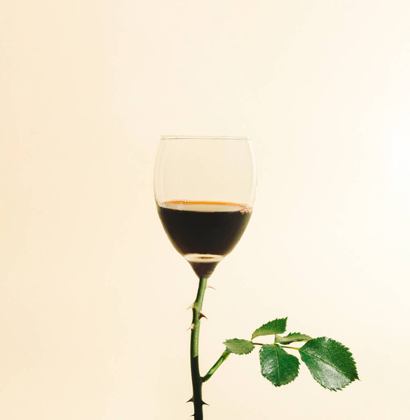 ベージュ地にバラ色の茎を持つワイングラス。最小限の休日の概念。バレンタインのお祝いのアイデア. - 写真・画像