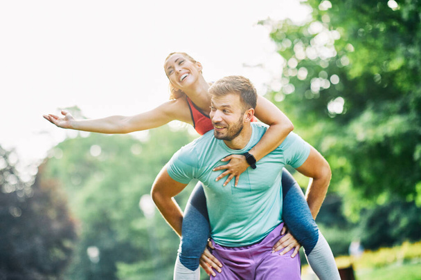 Portrait d'un jeune couple faisant de l'exercice et s'amusant dans un parc à l'extérieur - Photo, image