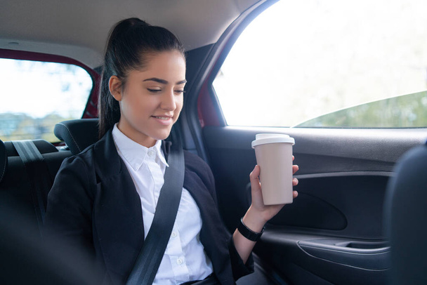 Business woman drinking coffee in car. - Фото, зображення