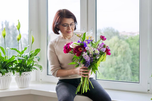 Porträt der schönen reifen Frau mit Blumenstrauß zu Hause - Foto, Bild