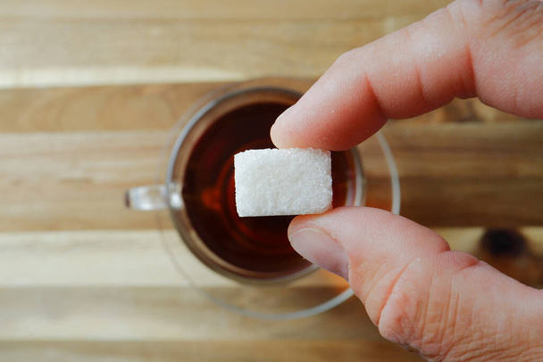 quelqu'un ajoute du sucre raffiné à une tasse de thé. - Photo, image
