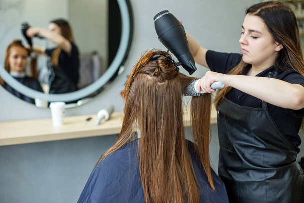barber dries his hair., cuts her hair to a girl with long hair. a woman dyes her hair, dries her hair with a hair dryer - Photo, Image