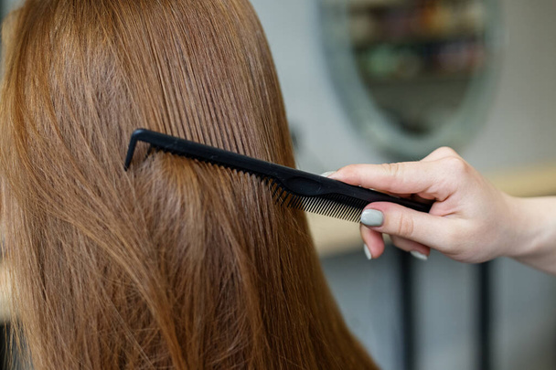 Egy nő a fodrászatban fésüli a hosszú haját. - Fotó, kép