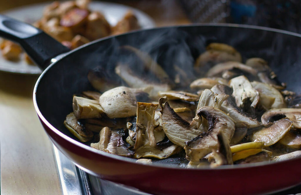 Top view of Fresh cut mushroom are being cooked in fry pan with steam coming out showing home cooking vegan concept - Φωτογραφία, εικόνα