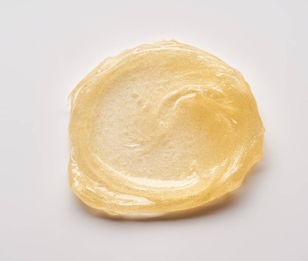 Transparent smear and texture of golden cosmetic gel on a white background. - Foto, immagini