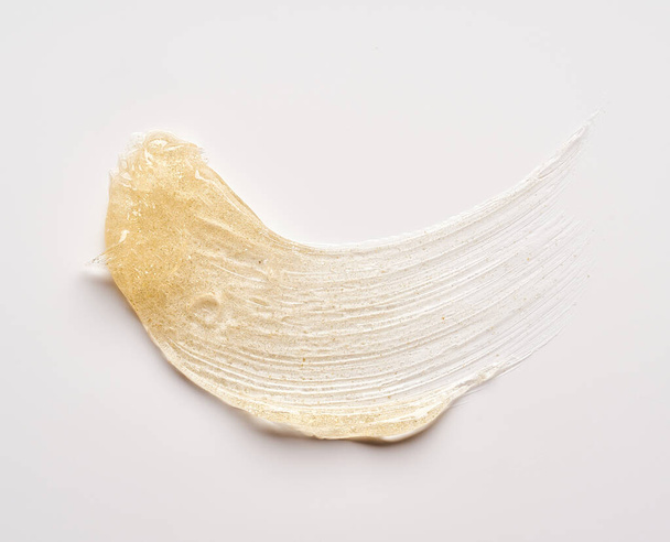 Transparent smear and texture of golden cosmetic gel on a white background. - Foto, immagini