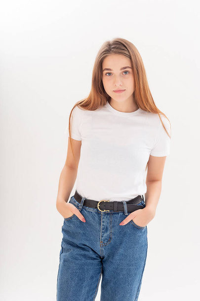 young caucasian pretty girl with long hair in t-shirt, blue jeans at studio - Фото, изображение