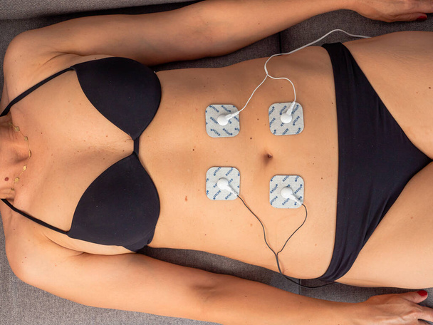 腹部の筋肉に配置された電極で治療中の女性,外傷後リハビリテーション,治療 - 写真・画像