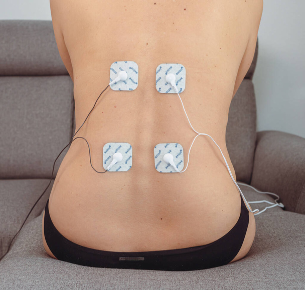 Sırt kaslarına elektrotlar yerleştirilmiş bir kadın, travma sonrası rehabilitasyon, tedavi - Fotoğraf, Görsel