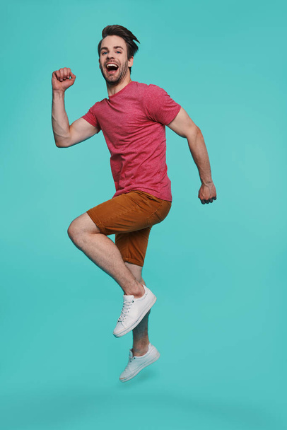 Full length of excited young man in casual clothing jumping and looking at camera - Fotoğraf, Görsel