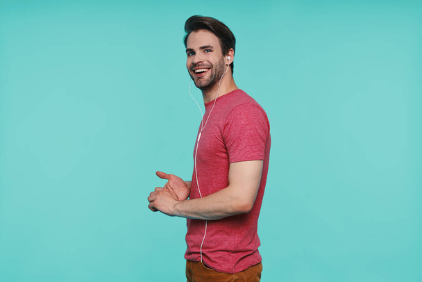 Side view of handsome young man in headphones looking at camera and smiling - Photo, image