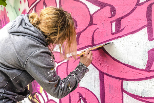 WETZLAR, ALEMANHA 23.05.2021: Jovem Artista feminina fazendo tipografia artificial senic grafite colorido na fachada da casa em WETZLAR; ALEMANHA - Foto, Imagem
