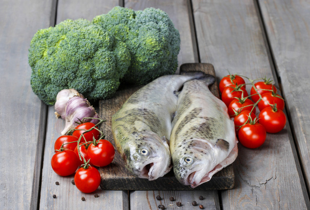 Two rainbow trouts, tomatoes and garlic on rustic wooden table - Photo, Image
