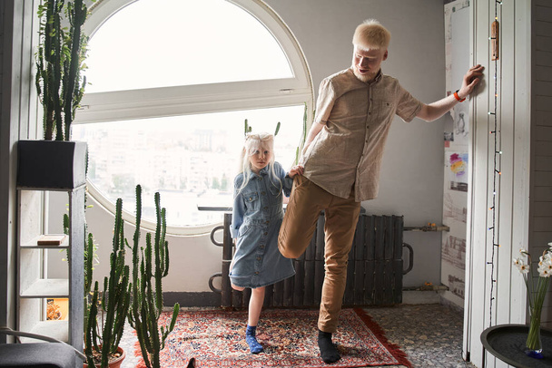 Albino child doing morning exercises with her blonde father at home - Zdjęcie, obraz
