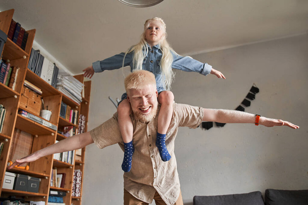 Parent is holding child while kid is putting up arms like plane - Фото, зображення