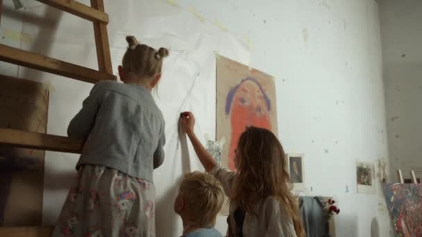 黒チョークで壁に絵を描く女性画家や子供のバックビュー. - 映像、動画