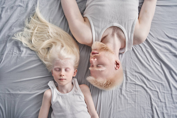 Man laying with his cute blonde daughter together at the bed with closed eyes - Valokuva, kuva