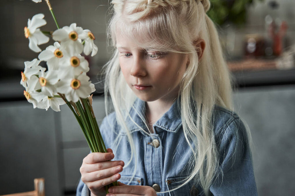 Masada duran ve vazoya çiçek koymaya hazırlanan kız. - Fotoğraf, Görsel