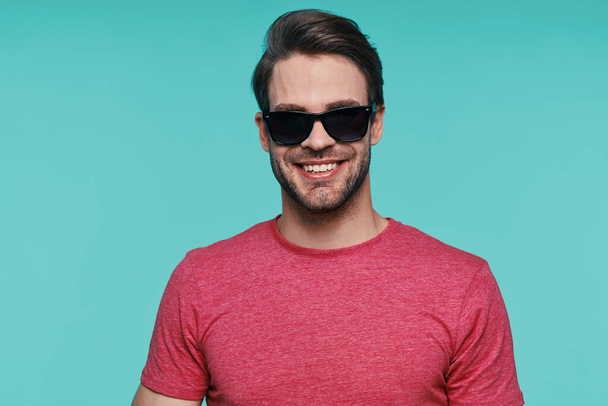 Portrait of handsome young man in sunglasses looking at camera and smiling - Foto, Imagem