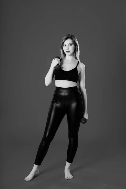 brown-haired woman in black leggings and a T-shirt goes in for sports. black and white photography - Photo, image