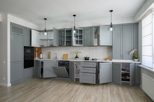 Trendy grijze en witte moderne keukenmeubels met deuren open - Foto, afbeelding