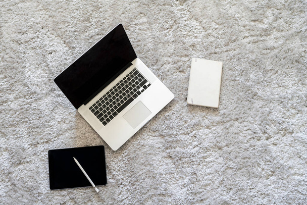 laptop i inne urządzenia na podłodze na miękkim dywanie w salonie w domu, izolacja podczas pandemii koronawirusowej - Zdjęcie, obraz