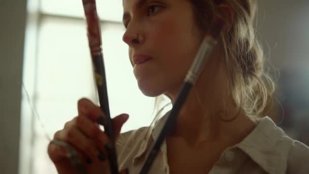 Inspirujący malarz szukający w pracowni artystycznej. Skupiona dziewczyna trzyma narzędzia w pomieszczeniach. - Materiał filmowy, wideo