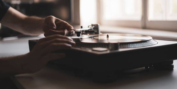 a close up persons hand put the needle on a record, playing vinyl disc at the party - 写真・画像