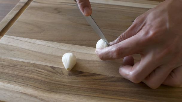 Finely chop the garlic with a knife on a cutting board - Foto, afbeelding