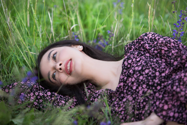 Young relaxed girl enjoys rest lying among wildflowers on a summer day. - Photo, Image