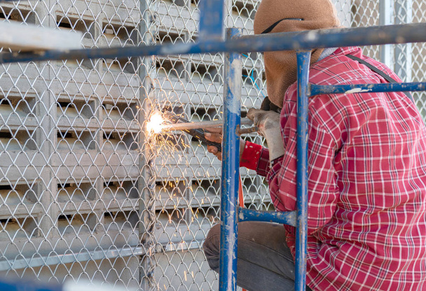 lavoratore utilizzato rete metallica di saldatura elettrica per fare porta del garage in fabbrica.. - Foto, immagini