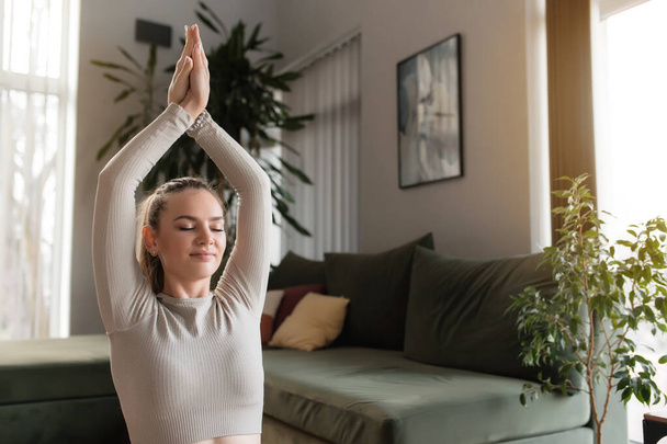 Vrij blanke jonge vrouw doen oefening workout en het beoefenen van yoga thuis in de woonkamer, mediteren en ontspannen. Hoge kwaliteit foto - Foto, afbeelding