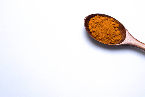 Turmeric powder in a wooden spoon on a white background. - Foto, Imagem