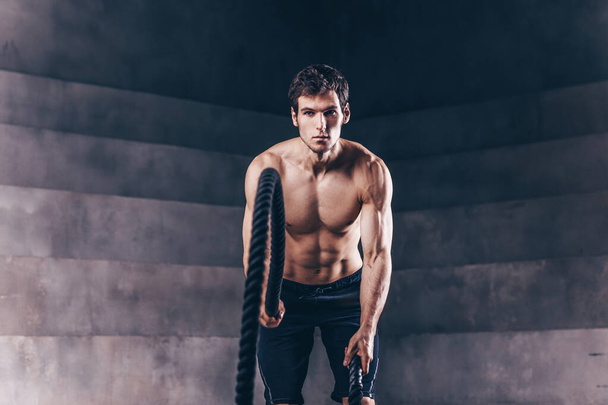 Muscular man working out with heavy ropes. - 写真・画像