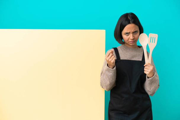 Молода змішана раса готує жінку з великим плакатом ізольовані на синьому фоні, роблячи гроші жестом, але зруйновані
 - Фото, зображення