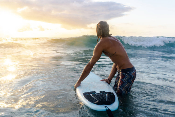 Young caucasian man get up early to  doing surf at sunrise - Photo, Image