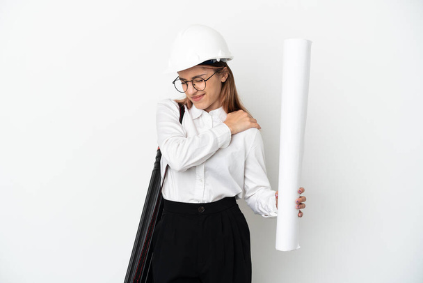 Giovane architetto donna con casco e tenere cianografie isolate su sfondo bianco che soffre di dolore alla spalla per aver fatto uno sforzo - Foto, immagini