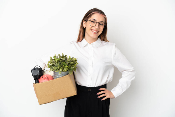 Young caucasian woman moving in new home among boxes isolated on white background posing with arms at hip and smiling - Photo, Image