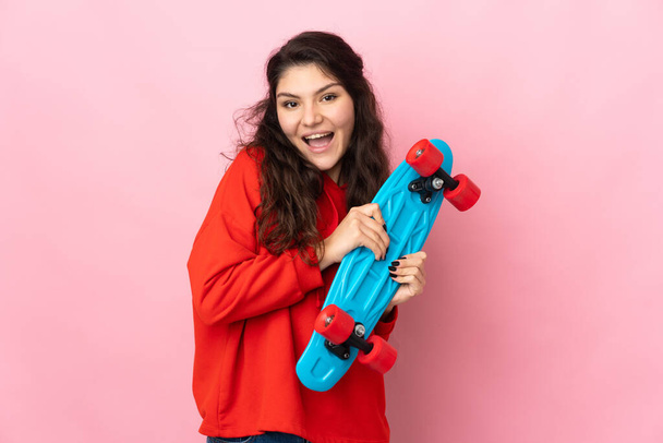 Teenager Russian girl isolated on pink background with a skate with happy expression - Photo, Image