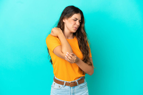 Νεαρή καυκάσια γυναίκα απομονωμένη σε μπλε φόντο με πόνο στον αγκώνα - Φωτογραφία, εικόνα