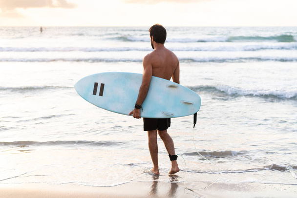 Giovane uomo caucasico alzarsi presto per fare surf all'alba - Foto, immagini