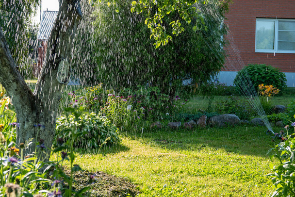 Smart Garten aktiviert mit vollautomatischer Sprinklerbewässerung, die frühmorgens im grünen Park Rasenbewässerung - Foto, Bild