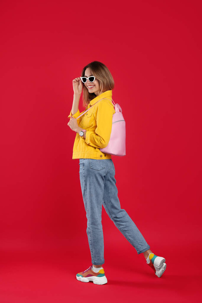 Happy woman with backpack on red background - Φωτογραφία, εικόνα
