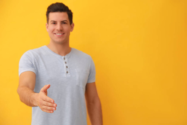 Man offering handshake against yellow background, focus on hand. Space for text - Фото, зображення